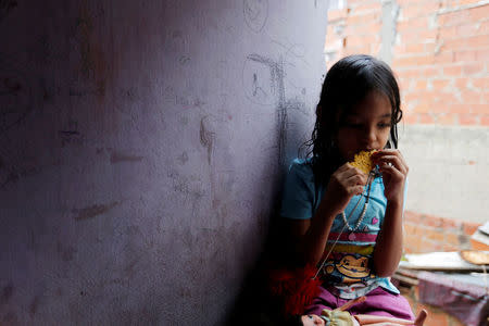 One of Yennifer Padron and Victor Cordova's daughters eats an arepa in the family room of the house that they share at Petare slum in Caracas, Venezuela, August 21, 2017. REUTERS/Andres Martinez Casares/Files