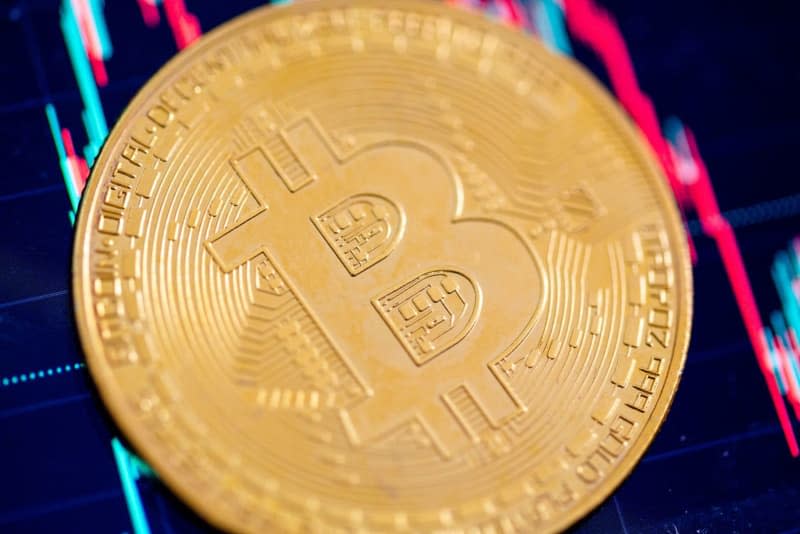 A coin bearing the logo of the bitcoin cryptocurrency lies on a table. Fernando Gutierrez-Juarez/dpa