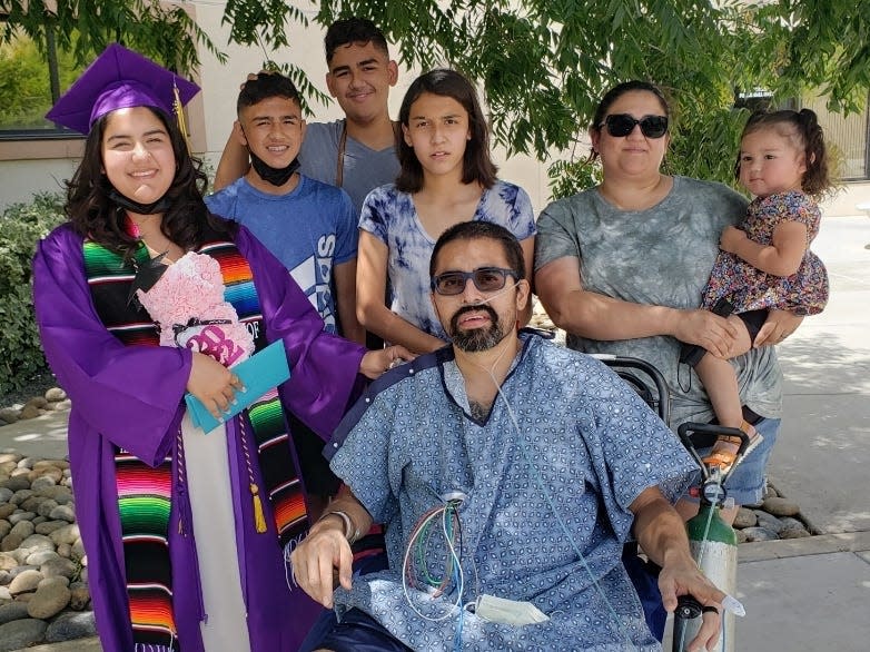 Jose Leon sits with his family around him at his daughter's high school graduation