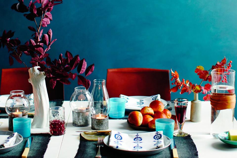 Bold and dramatic table setting with various tones of blue, orange and red and candles on the table