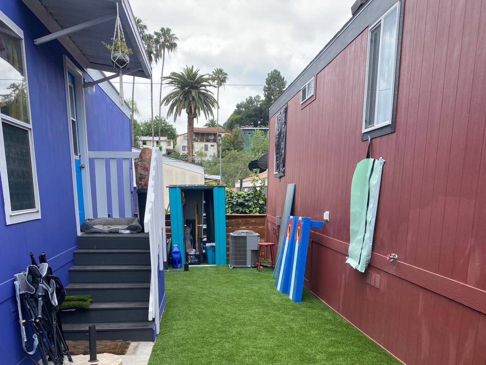A green area of Astroturf between a blue and a red mobile home