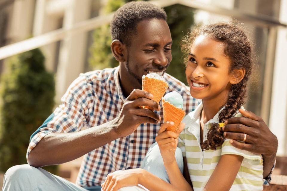 girl and father enjoying ice cream and smiling