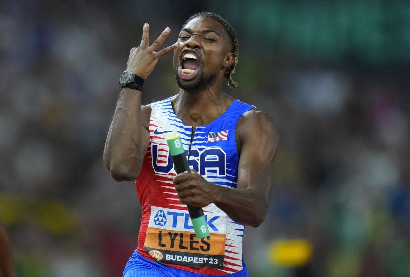 Noah Lyles holds up three fingers as he celebrates anchoring his team to gold in the Men's 4x100-meters relay