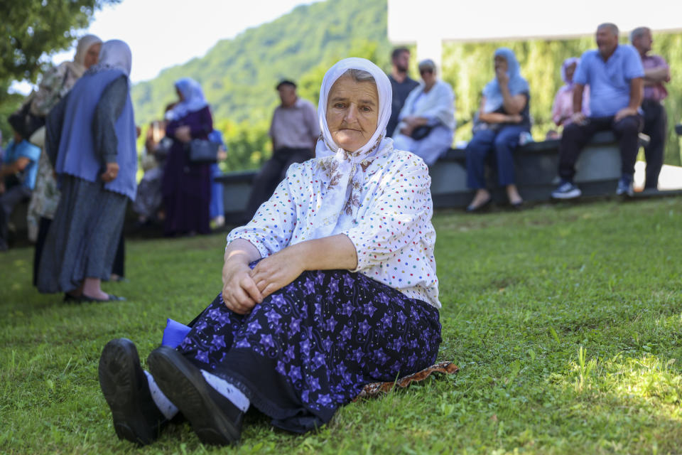 A Muslim women rests in Visoko, Bosnia, Sunday, July 9, 2023 next to a truck carrying 30 coffins with remains of the recently identified victims of the 1995 Srebrenica genocide. So far, the remains of more than 6,600 people have been found and buried at a vast and ever-expanding memorial cemetery in Potocari, outside Srebrenica. (AP Photo/Armin Durgut)