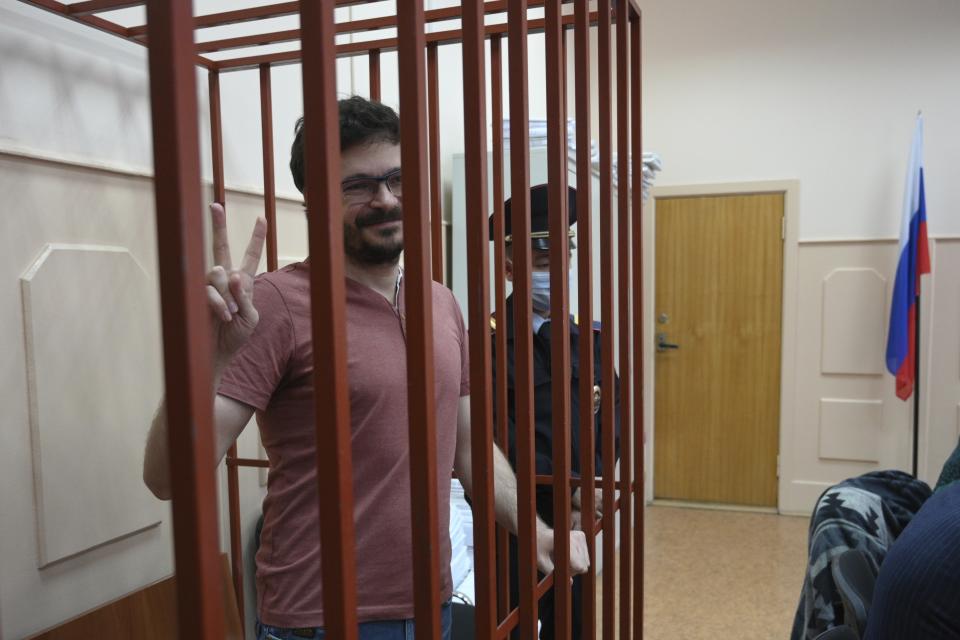 Russian opposition activist and municipal deputy of the Krasnoselsky district Ilya Yashin gestures standing in a cage during a hearing on his detention, at the Basmanny district court in Moscow, Russia, Friday, Sept. 9, 2022. Yashin, 39, is one of the few prominent opposition figures that refused to leave Russia despite the unprecedented pressure the authorities have mounted on dissent in recent years. (AP Photo/Dmitry Serebryakov)