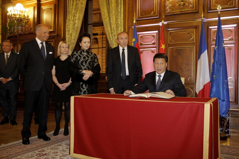 Chinese President Xi Jinping, right, signs a guest book as he is welcomed by Lyon's mayor Gerard Collomb, second right, and French foreign minister Laurent Fabius, left, before a dinner at the town hall in Lyon, central France, Tuesday, March 25, 2014. Xi Jinping arrived in France for a three-day state visit. (AP Photo/Laurent Cipriani, Pool)