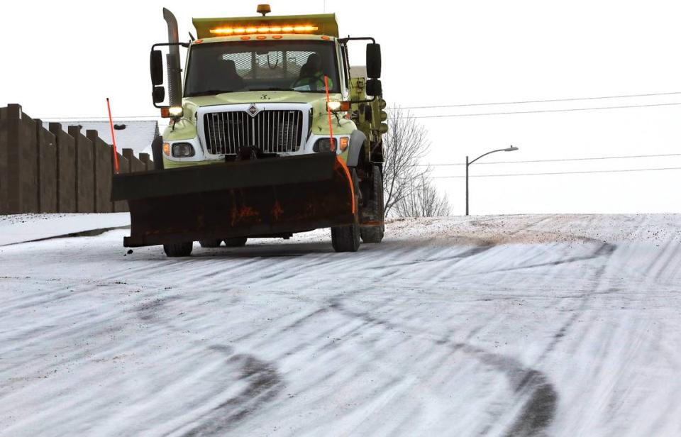 A Kennewick city snowplow applies layer of salt on the steep section South Kellogg Street near West 38th Court Thursday morning before the start of a predicted winter storm.