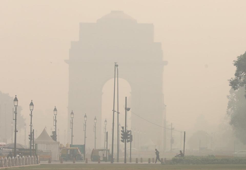 Pedestrians cross a street as the city is engulfed in heavy smog at Rajpath, in New Delhi (EPA)