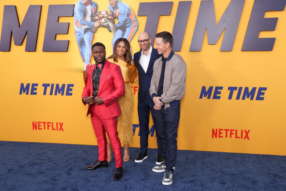 Kevin Hart in a red suit, Regina Hall in a yellow dress, John Hamburg in a black suit, and Mark Wahlberg in a grey jacket and jeans