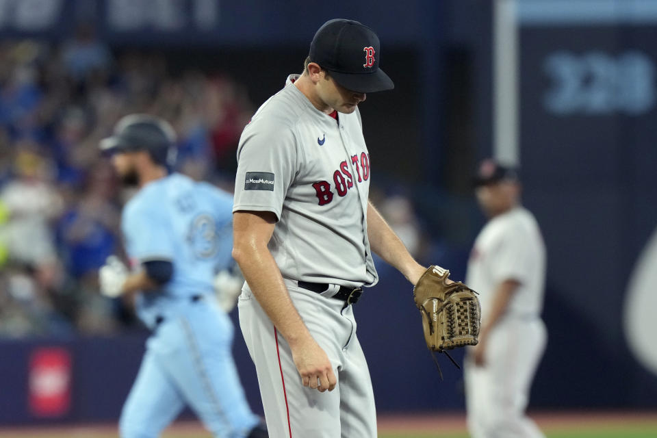 Boston Red Sox starting pitcher Garrett Whitlock, foreground, reacts as Toronto Blue Jays designated hitter Brandon Belt, back left, rounds the bases after hitting a solo home run during first-inning baseball game action in Toronto, Sunday, July 2, 2023. (Frank Gunn/The Canadian Press via AP)