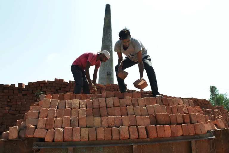 This photograph taken on September 16, 2017, shows Indian labourers loading bricks onto a tractor trolley at a brick kiln on the outskirts of Amritsar