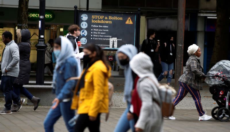 People walk past an information board following the outbreak of the coronavirus disease (COVID-19) in Bolton, Britain