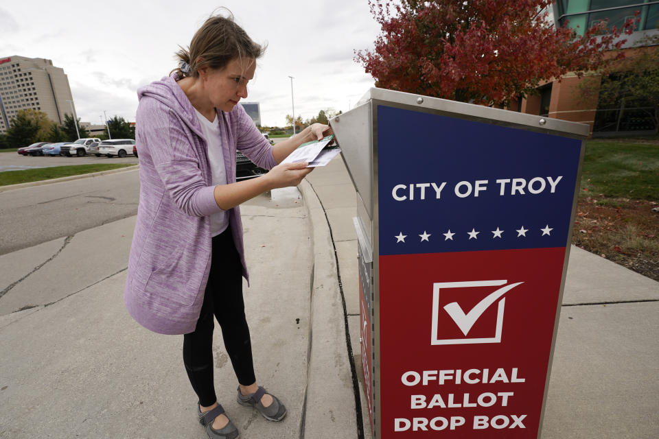 Nikki Schueller inserts her absentee voter ballot into a drop box in Troy, Mich., Thursday, Oct. 15, 2020. (AP Photo/Paul Sancya)