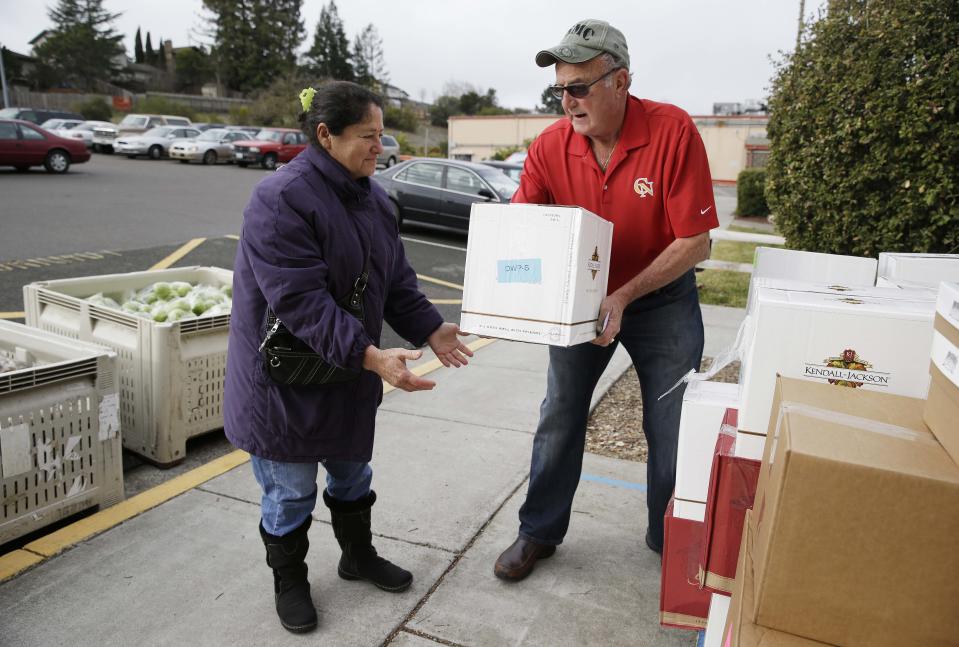 This photo taken Jan. 8, 2014 shows Steve Bosshard, right, handing over a specially prepared box of food to Maria Gonzalez, left, at a food bank distribution in Petaluma, Calif., as part of a research project with Feeding America to try to improve the health of diabetics in food-insecure families. Doctors are warning that the federal government could be socked with a bigger health bill if Congress cuts food stamps _ maybe not immediately, they say, but if the poor wind up in doctors' offices or hospitals as a result. (AP Photo/Eric Risberg)