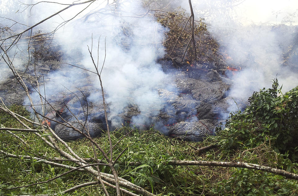 In this Oct. 27, 2014 photo provided by the U.S. Geological Survey, lava flow from Kilauea Volcano that began on June 27 burns through thick vegetation below the pasture downslope of the Pahoa cemetery near the town of Pahoa on the Big Island of Hawaii. Residents of the small town have had weeks to prepare for what's been described as a slow-motion disaster. County officials are making arrangements for those living in the lava's path to be able to watch the lava destroy their homes as a means of closure.  (AP Photo/U.S. Geological Survey)