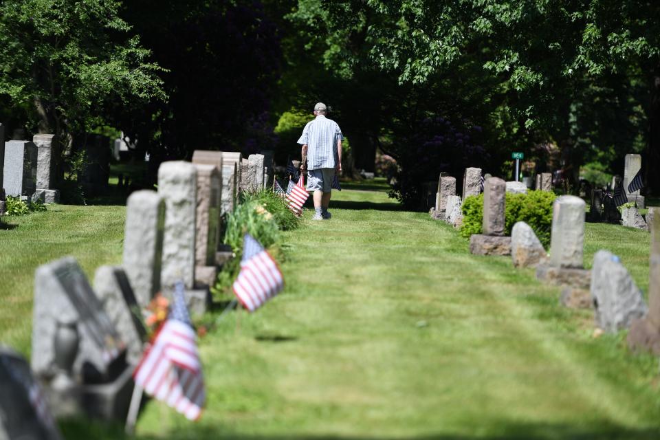 Kent American Legion Post 496 member Paul Sellman walks a line of graves with American flags on Thursday, May 23, 2024, at Standing Rock Cemetery in Kent.