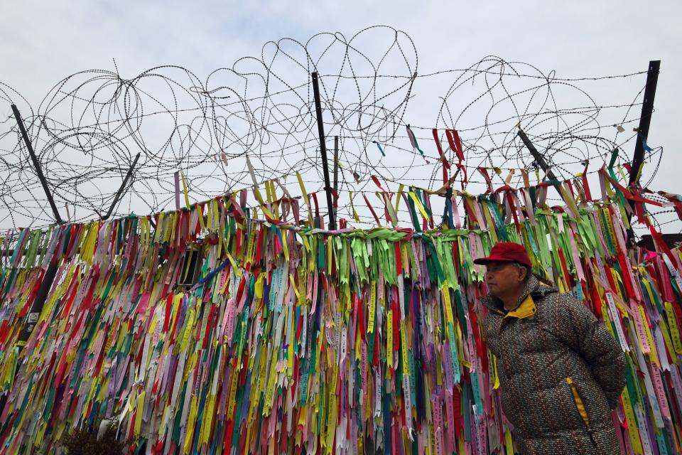 A man walks past a military fence covered with ribbons calling for peace and reunification at the Imjingak peace park near the Demilitarized Zone (DMZ) dividing the two Koreas at the border city of Paju on Jan. 8, 2018.