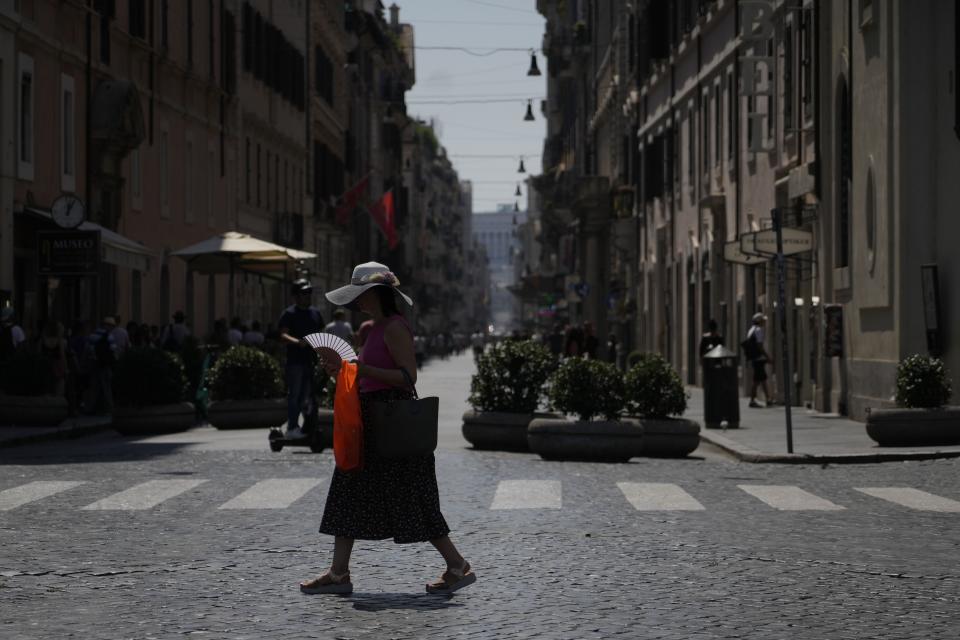 FILE - A woman waves her fan as she walks in downtown Rome, Aug. 22, 2023. UN weather agency says Earth sweltered through the hottest summer ever as record heat in August capped a brutal, deadly three months in northern hemisphere. (AP Photo/Gregorio Borgia, File)