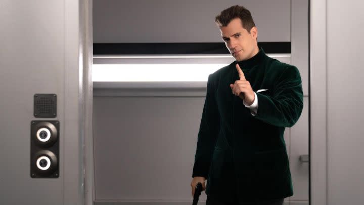 Henry Cavill as Agent Argylle pointing at someone off-camera in the film Argylle.