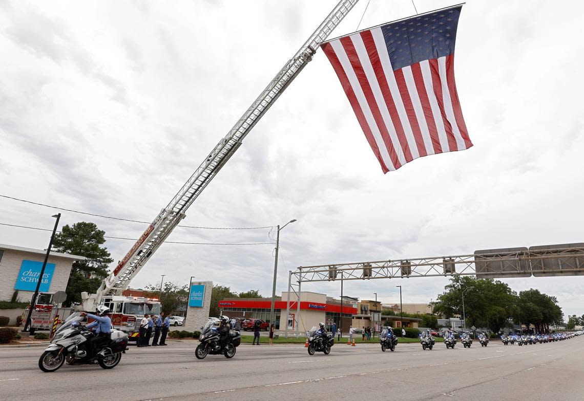 Law enforcement pass under a flag on Glenwood Avenue following the funeral for Wake County Deputy Ned Byrd on Friday, Aug. 19, 2022, in Raleigh, N.C. Byrd was found dead with multiple gunshot wounds early Friday morning, Aug. 12 in southeastern Wake County. Kaitlin McKeown/kmckeown@newsobserver.com