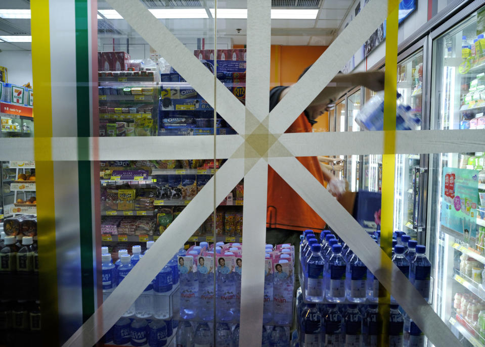 FILE - In this Saturday, Sept. 15, 2018, file photo, a convenience store glass wall is taped in preparation for approaching typhoon Mangkhut in Hong Kong. (AP Photo/Vincent Yu, File)