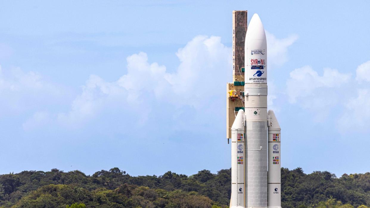  a white rocket upright on a launchpad 