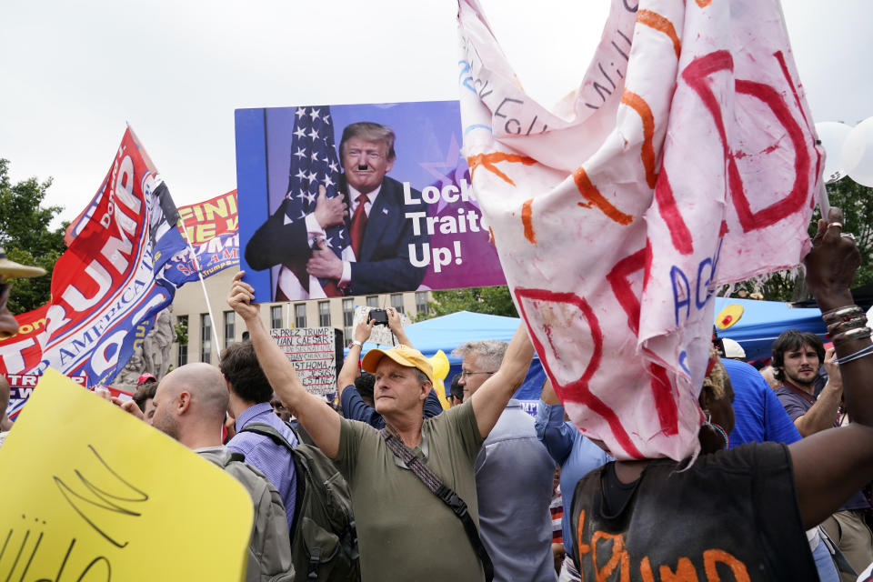 Eric Lamar sostiene un letrero contra Donald Trump mientras está rodeado por opositores y simpatizantes del expresidente estadounidense cerca del tribunal federal E. Barrett Prettyman, el jueves 3 de agosto de 2023, en Washington. (AP Foto/Jacquelyn Martin)