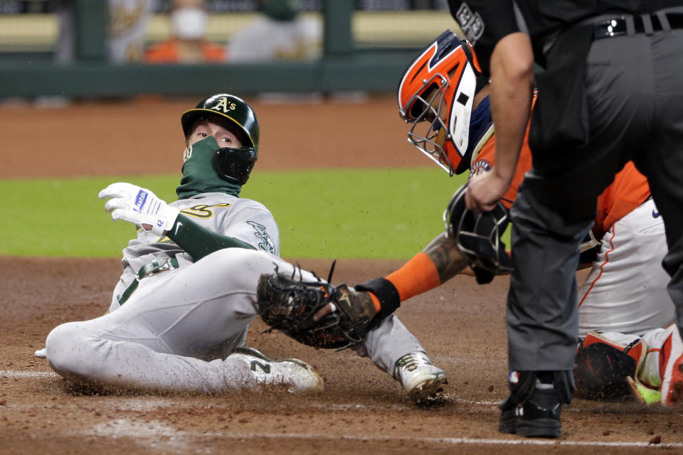 Oakland Athletics' Mark Canha, left, is out at the plate on a tag by Houston Astros catcher Martin Maldonado during the second inning of the first baseball game of a doubleheader Saturday, Aug. 29, 2020, in Houston. (AP Photo/Michael Wyke)