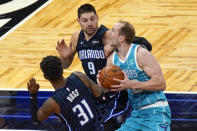 Charlotte Hornets center Cody Zeller, right, drives to the basket against Orlando Magic guard Terrence Ross (31) and center Nikola Vucevic (9) during the second half of an NBA basketball game, Monday, Jan. 25, 2021, in Orlando, Fla. (AP Photo/John Raoux)