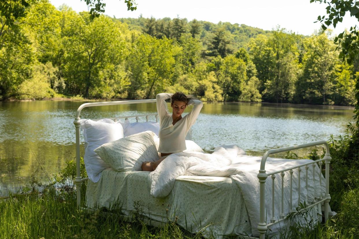 a person sitting on a bed outside by the water