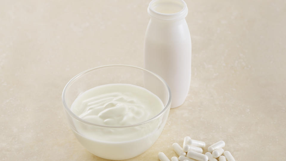 Probiotic pills next to a bowl of probiotic-filled yogurt and bottle of milk, which is beneficial for skin health