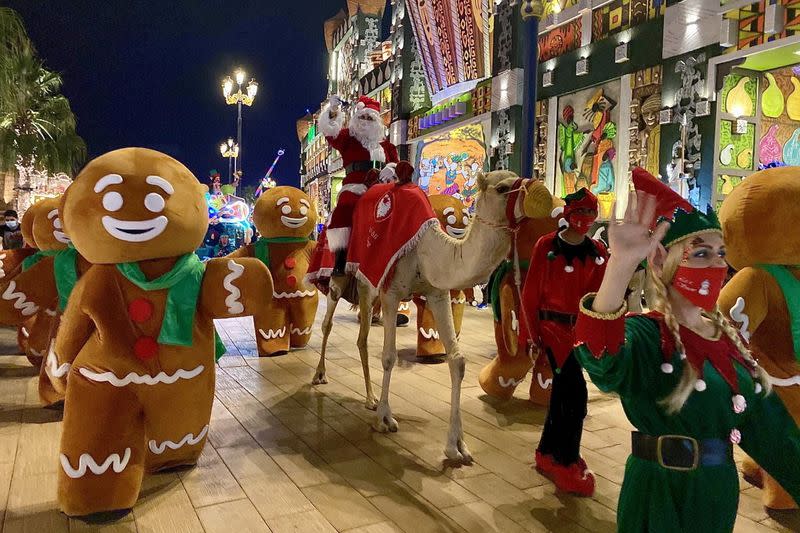A man dresses up as Santa Claus rides a camel at the Global Village