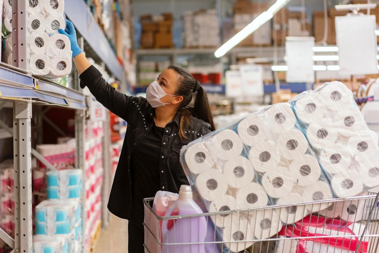 Woman in medical mask buying toilet paper in bulk