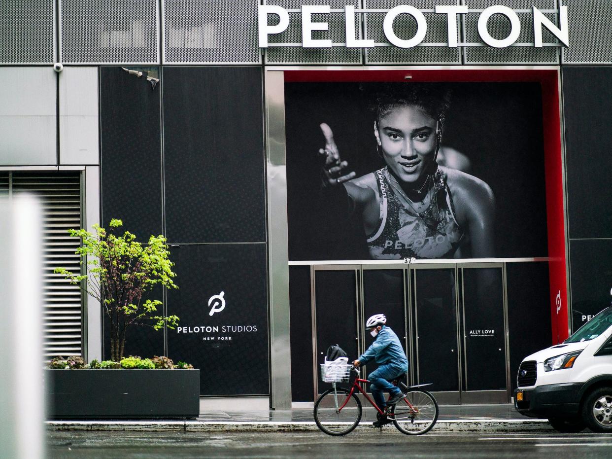 Man bikes in front of Peloton store featuring photo of instructor