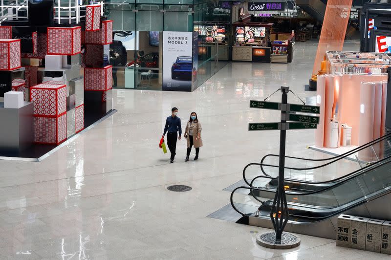 People wearing protective masks walk in a shopping district in Beijing