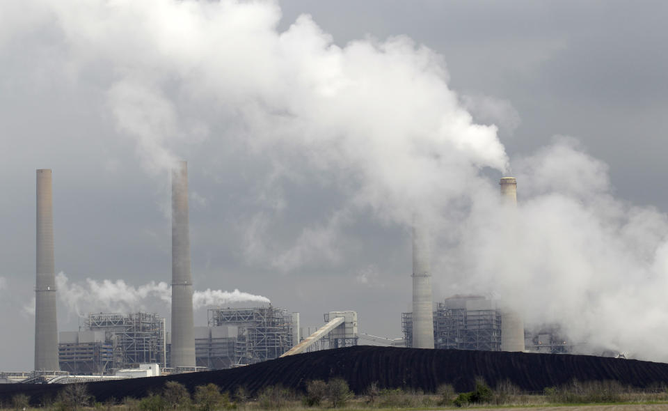 Exhaust rises from smokestacks in front of piles of coal in Texas. (Source: AP)