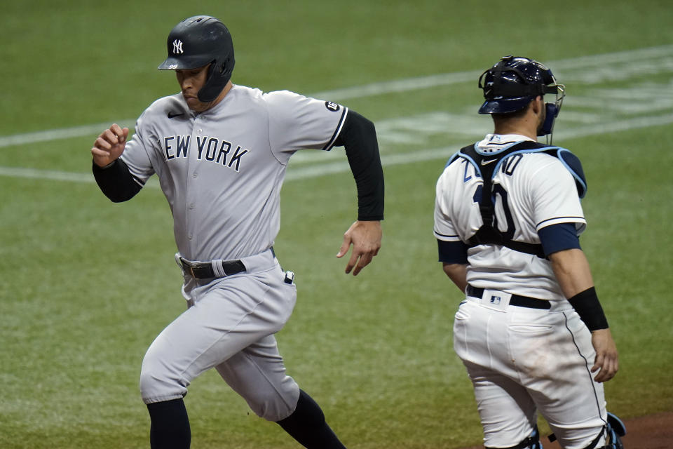 New York Yankees' Aaron Judge, left, scores past Tampa Bay Rays catcher Mike Zunino (10) on a sacrifice fly by Aaron Hicks during the seventh inning of a baseball game Wednesday, May 12, 2021, in St. Petersburg, Fla. (AP Photo/Chris O'Meara)