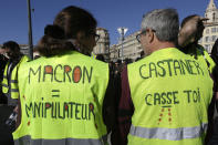 Yellow vest protesters wear jackets reading "Macron manipulative" and "Castaner go away" referring to French Interior Minister Christophe Castaner, during a demonstration Saturday, Feb.16, 2019 in Marseille, southern France. Yellow vest protesters are holding scattered demonstrations around Paris and the rest of France amid waning support for their movement. (AP Photo/Claude Paris)