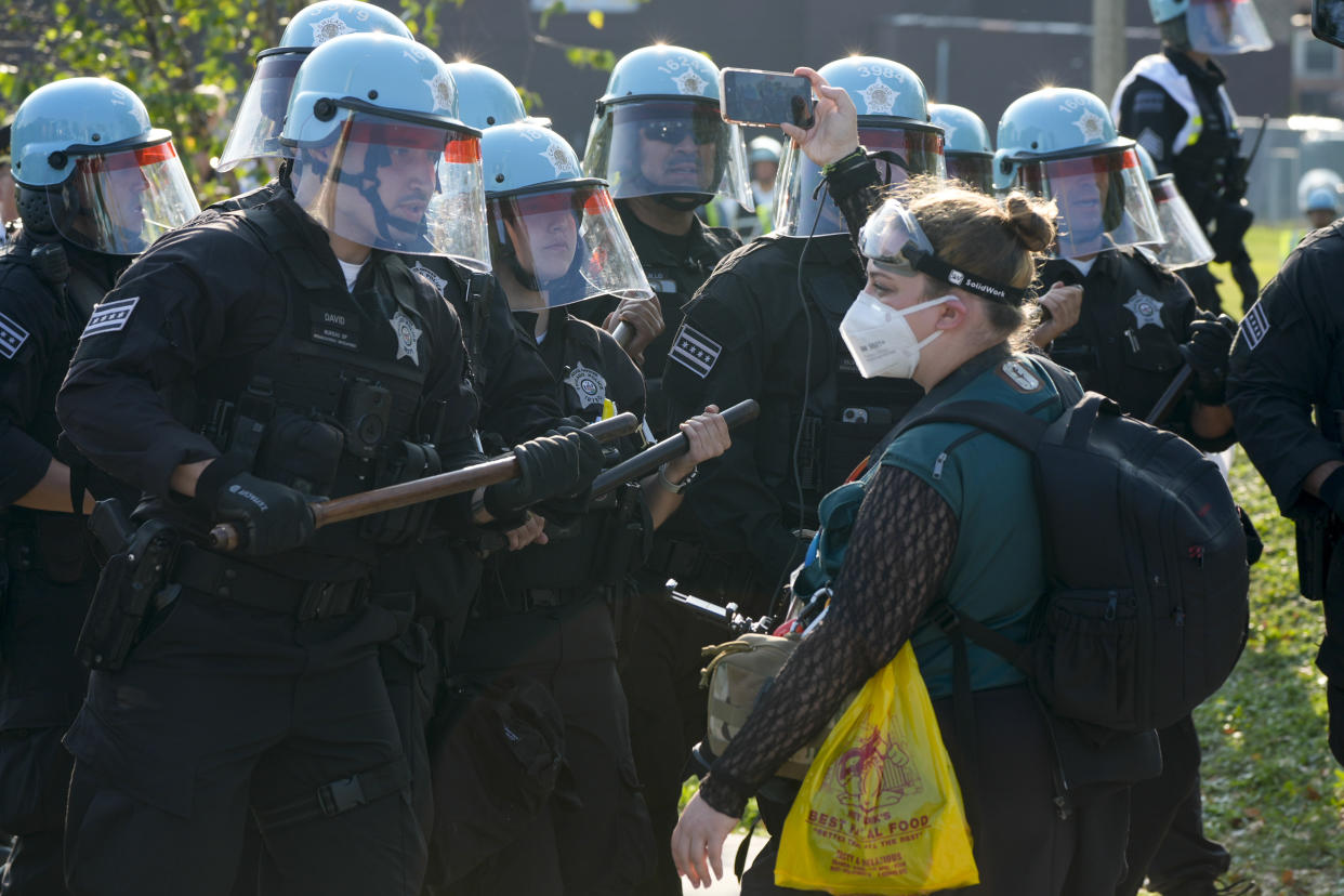 A protester in a COVID mask confronts helmeted police during a demonstration outside the Democratic National Convention in Chicago on Monday. 