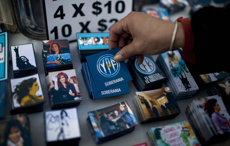 A woman picks up a magnet for sale that reads in Spanish "YPF. Sovereignty" outside Congress where lawmakers are debating the YPF bill on the expropriation of the oil company in Buenos Aires, Argentina, Thursday, May 3, 2012. President Cristina Fernandez, who pushed forward a bill to renationalize the country's largest oil company, said the legislation put to congress would give Argentina a majority stake in oil and gas company YPF by taking control of 51 percent of its shares currently held by Spain's Repsol. (AP Photo/Natacha Pisarenko)