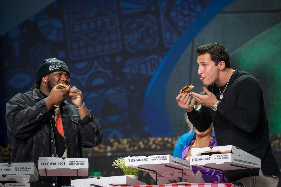 Detroit Lion Alim McNeill, left, takes a big bite out of Detroit-style pizza made by the Detroit Pizza Bar while New York Giants quarterback Tommy DeVito also digs in. It was part of a battle between Detroit-style pizza and New York-style pizza on the NFL draft's main stage on Saturday, April 27, 2024 in downtown Detroit.