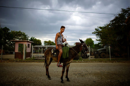 Mechanic Dayan Nunes, 20, sits on a donkey in the village of La Merced, in the Sierra Maestra, Cuba, April 1, 2018. REUTERS/Alexandre Meneghini