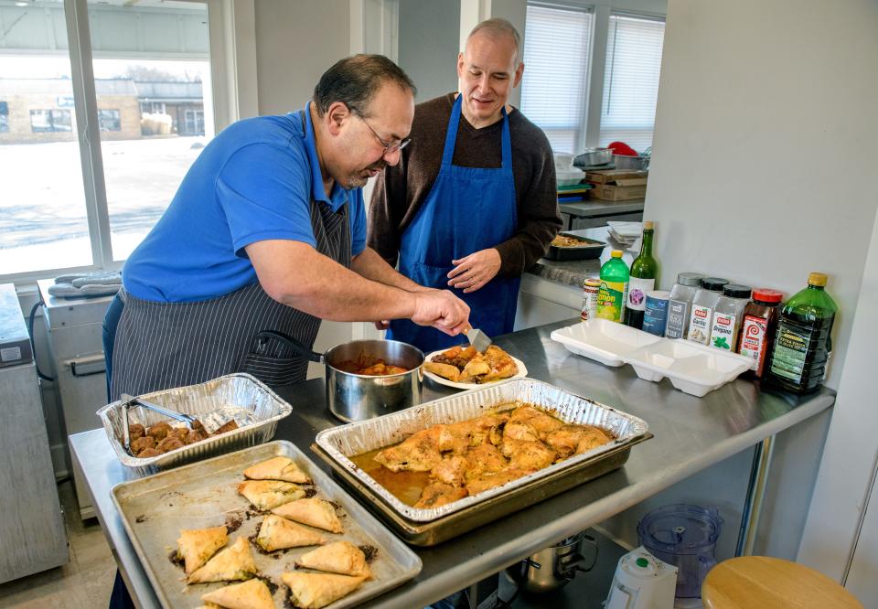 Phil Harris, left, and Darren Rockhold serve up some of the Greek fare they prepare in the kitchen of a former residence that now serves as the headquarters of Phil's Mediterranean & American Catering at 109 W. Chicago St. in Morton. 