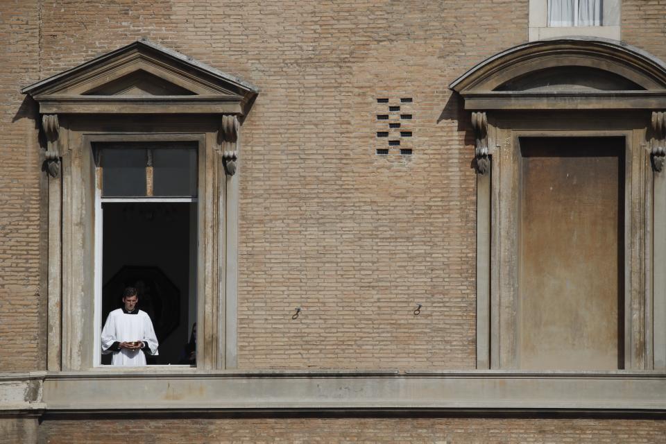 A priests looks out from a window during a canonization Mass in St. Peter's Square at the Vatican, Sunday, Oct. 13, 2019. Pope Francis on Sunday canonized Cardinal John Henry Newman, the 19th-century Anglican convert who became an immensely influential, unifying figure in both the Anglican and Catholic churches. Francis presided over Mass on Sunday in a packed St. Peter's Square to declare Newman and four women saints. (AP Photo/Alessandra Tarantino)