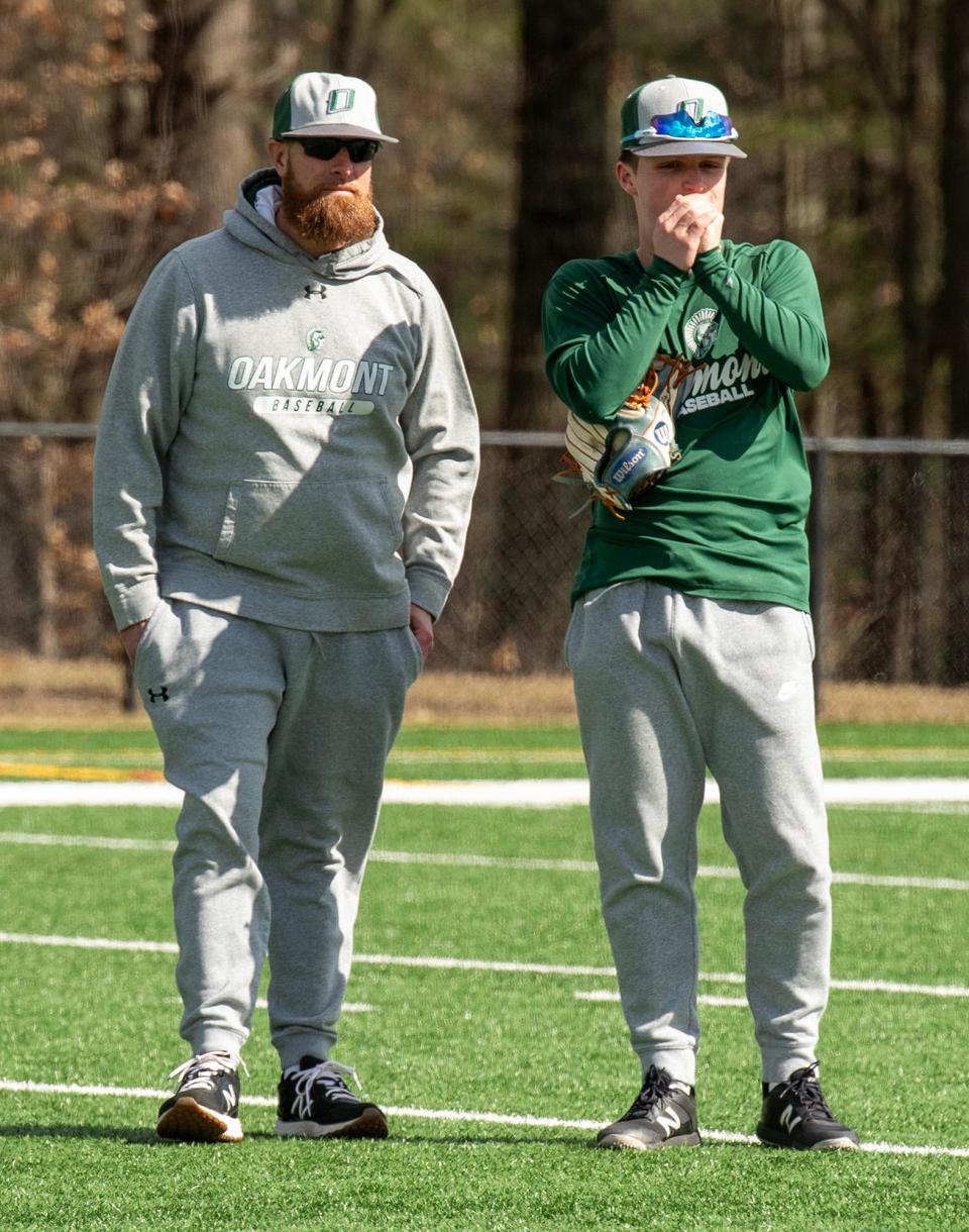 Oakmont infielder Sam Curtis warms his hands while chatting with coach Tim Caouette on the first day of practice Monday, March 18, 2024.