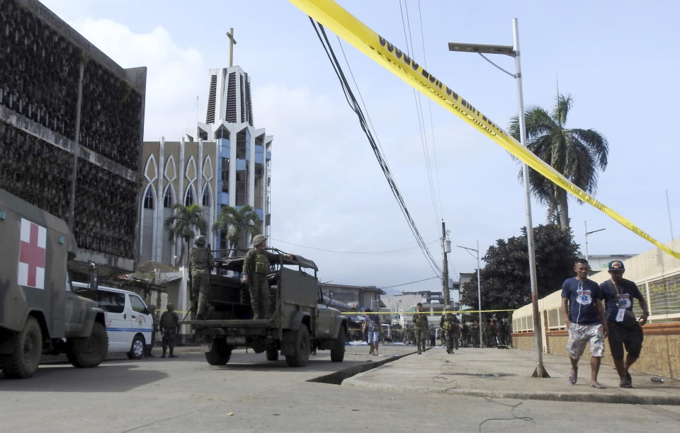 Police investigators and soldiers attend the scene after two bombs exploded outside a Roman Catholic cathedral in Jolo, the capital of Sulu province in southern Philippines, Sunday, Jan. 27, 2019. Two bombs minutes apart tore through a Roman Catholic cathedral on a southern Philippine island where Muslim militants are active, killing at least 20 people and wounding more than 80 others during a Sunday Mass, officials said. (AP Photo/Nickee Butlangan)