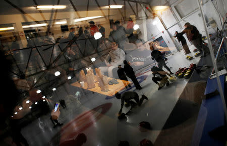 People are reflected in the window as refugees learn the sport of curling at the Royal Canadian Curling Club during an event put on by the "Together Project", in Toronto, March 15, 2017. REUTERS/Mark Blinch