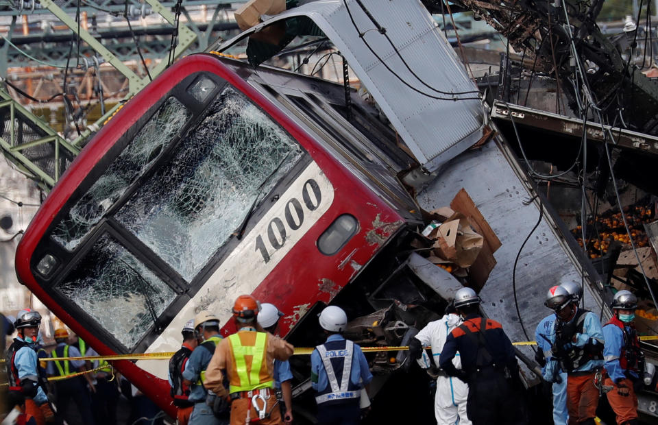 Rescue officers, police and railway company employees work at the scene where a train derailed during a collision with a truck in Yokohama, near Tokyo, Japan September 5, 2019. REUTERS/Issei Kato