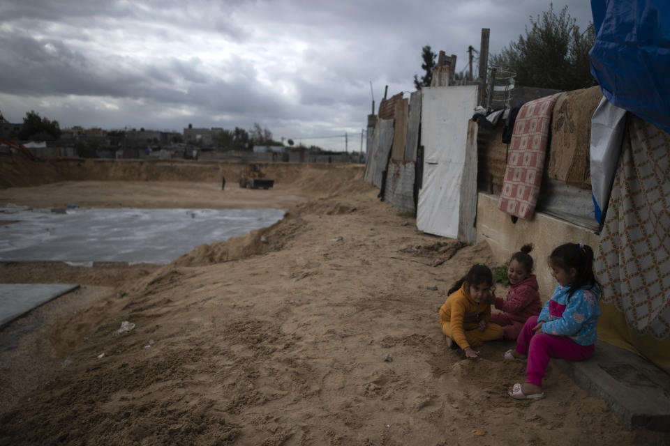 Palestinian children play outside their family home next to concrete slab foundations for one of three Egyptian-funded housing complexes in the Gaza Strip, in the town of Beit Lahiya, northern Gaza, Thursday, Jan. 20, 2022. After years of working behind the scenes as a mediator, Egypt is taking on a much larger and more public role in Gaza. In the months since it brokered a Gaza cease-fire last May, Egypt has sent crews to clear rubbled and promised to build vast new apartment complexes, and billboards of its president Abdel-Fattah el-Sissi, are a common sight. (AP Photo/Khalil Hamra)