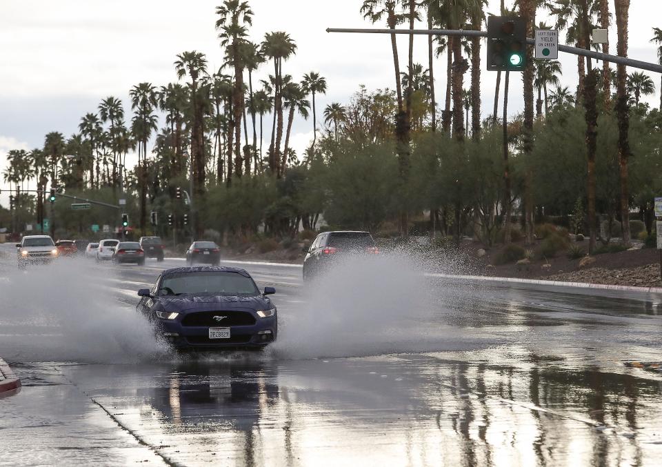 A car splashes through an intersection at Ramon Road and Farrell Drive in Palm Springs, Calif.